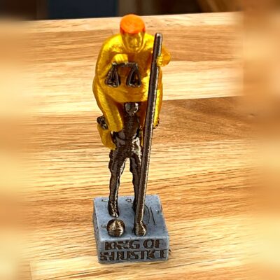 The Orange Plague set forfra – 3D-printet figur med vægt og stav på sokkel med teksten King of Injustice